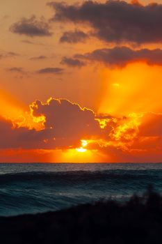 Stunning sunrise at Akumal Beach, México with vibrant orange hues and dramatic clouds.