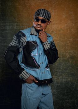 Confident man posing in trendy denim outfit with sunglasses.