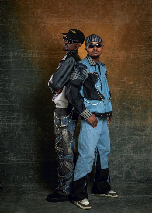 Free Two adults in fashionable denim and chains pose for a portrait in a studio setting. Stock Photo