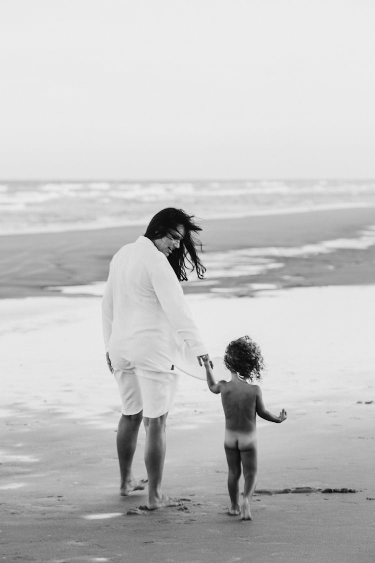 Woman And Nude Toddler Walking At The Beach