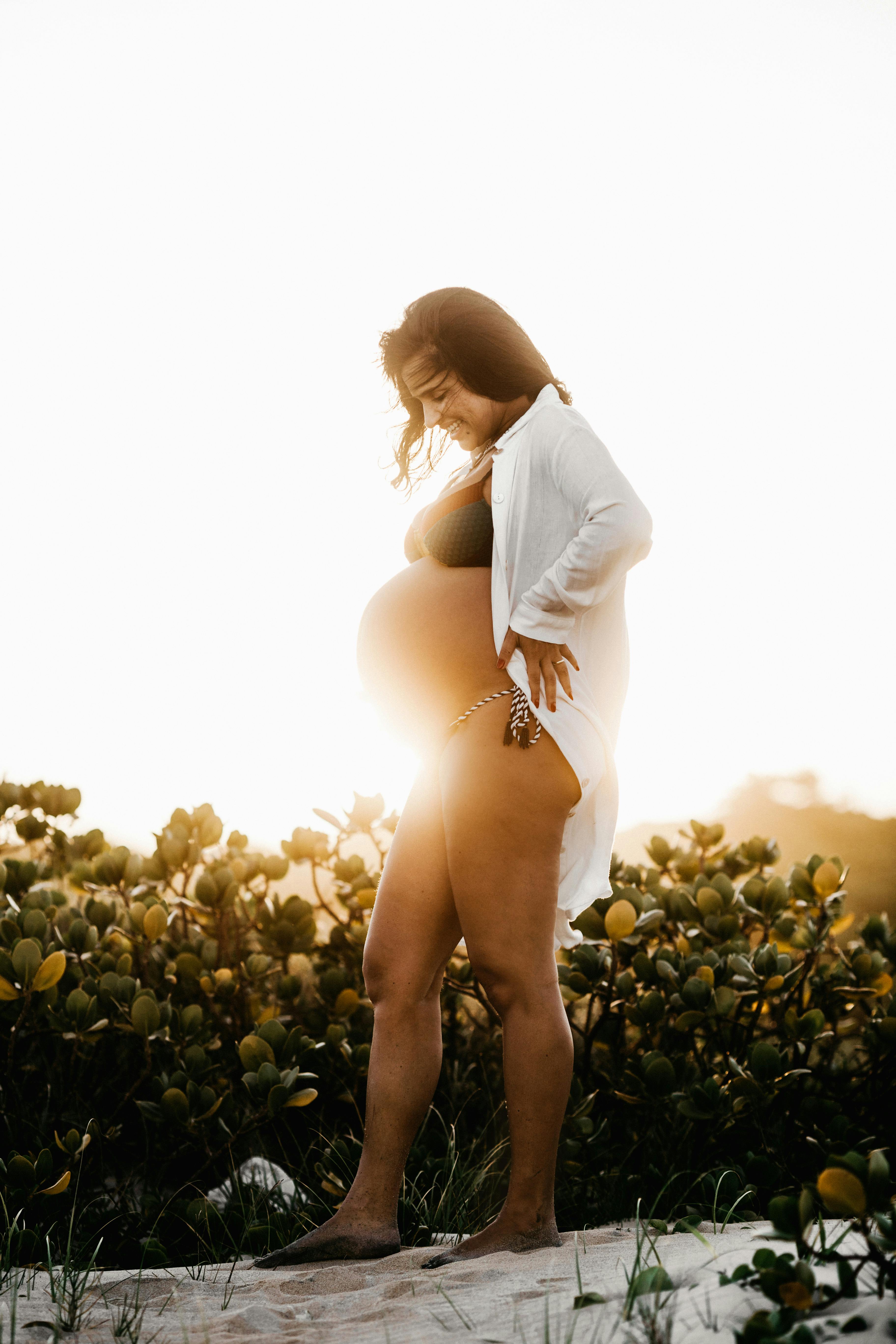 pregnant woman standing beside plants