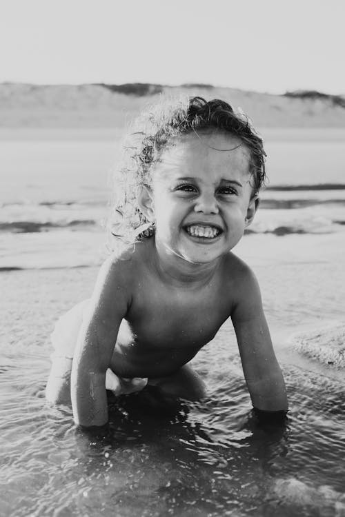 Grayscale Photography Of Smiling Toddler On Body Of Water