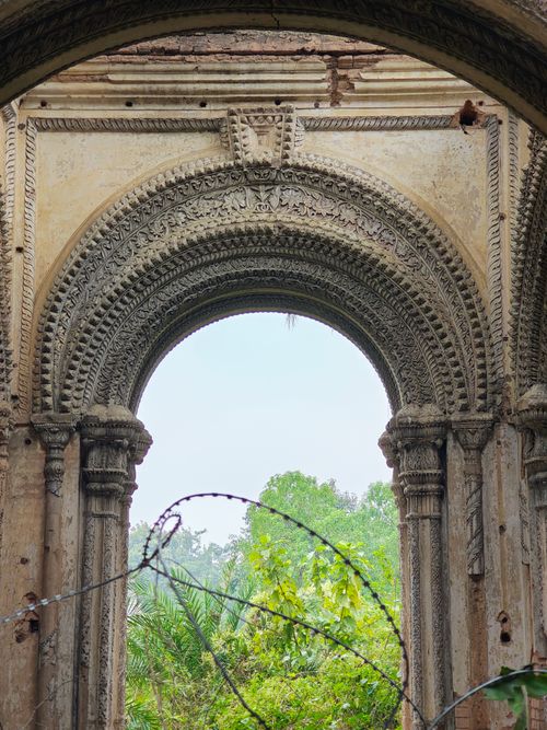 Free An ornate archway from ancient ruins with lush greenery peeking through, showcasing intricate architectural details. Stock Photo