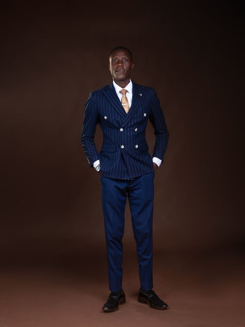 Free Portrait of a man in a sophisticated pinstripe suit posing confidently against a dark background. Stock Photo
