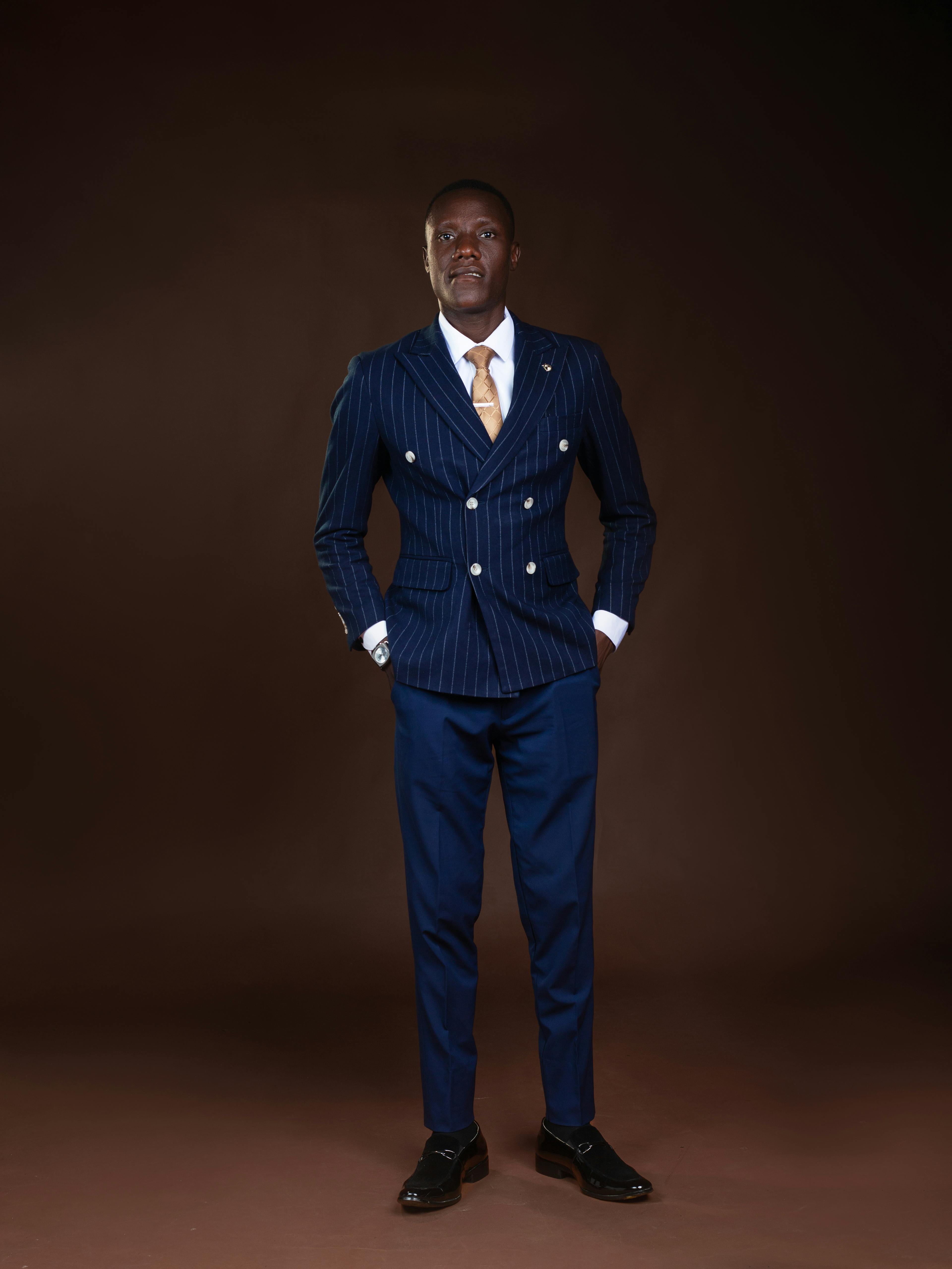 Gratis Retrato de un hombre con un sofisticado traje de raya diplomática posando con confianza sobre un fondo oscuro. Foto de stock