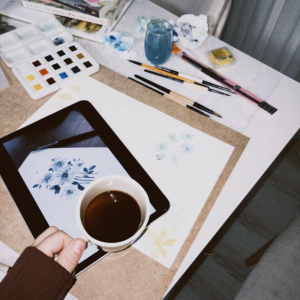 Art desk with watercolour pans, brushes and a floral illustration — photo by mrvphoto. on Pexels