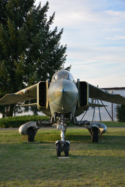 Free Front view of a military jet on grass, set against a clear sky. Stock Photo