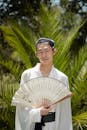 Traditional Asian Attire with Decorative Fan Outdoors