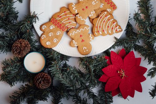 Free Gingerbread cookies and Christmas decor on table with candle and poinsettia. Stock Photo