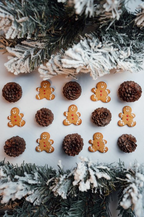 Free Flat lay of gingerbread men and pinecones with snowy branches, perfect for holiday-themed visuals. Stock Photo