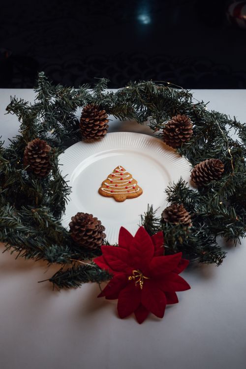 Free Christmas wreath with pine cones, cookie, and poinsettia on a plate. Stock Photo
