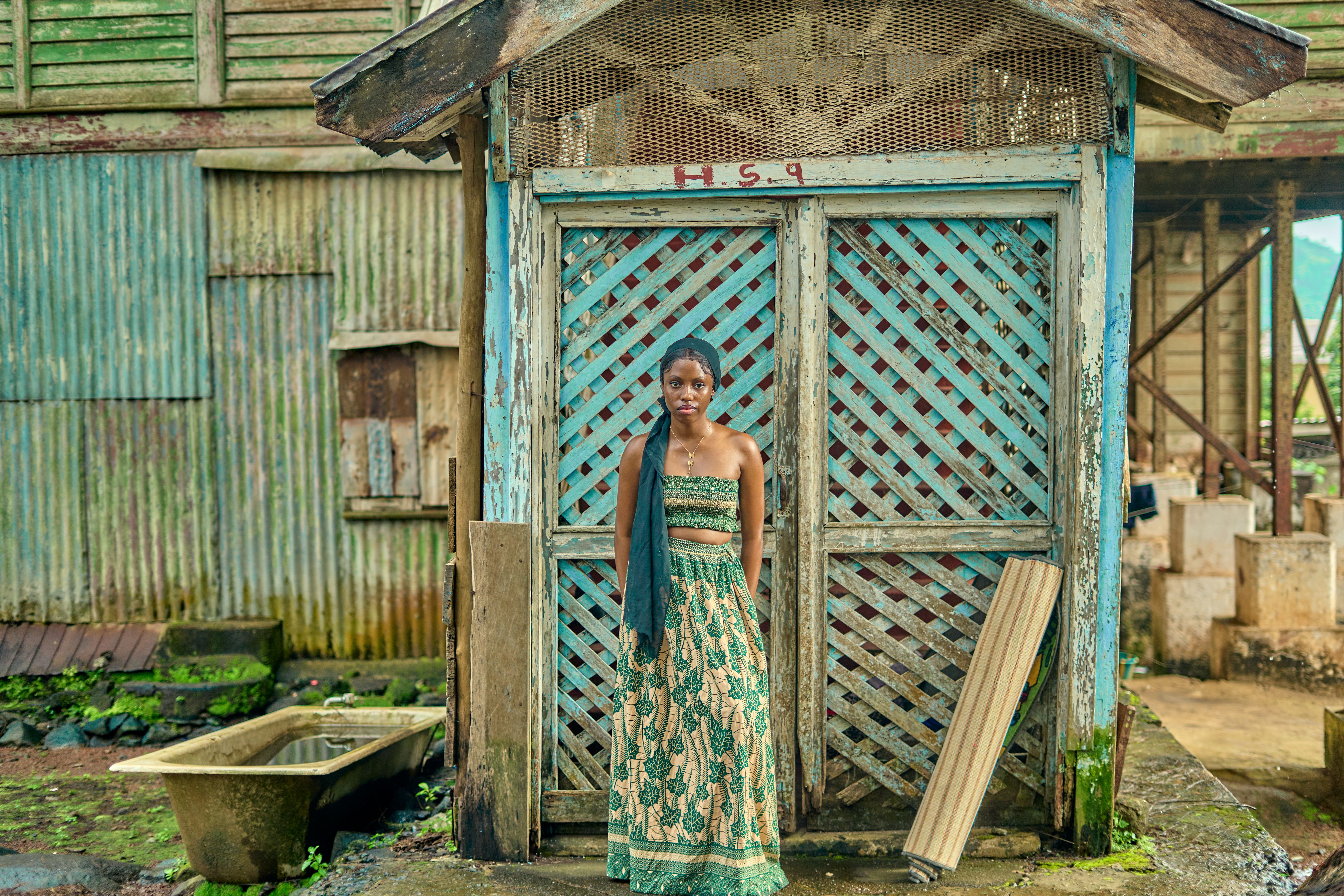 Woman in traditional attire by rustic hut · Free Stock Photo