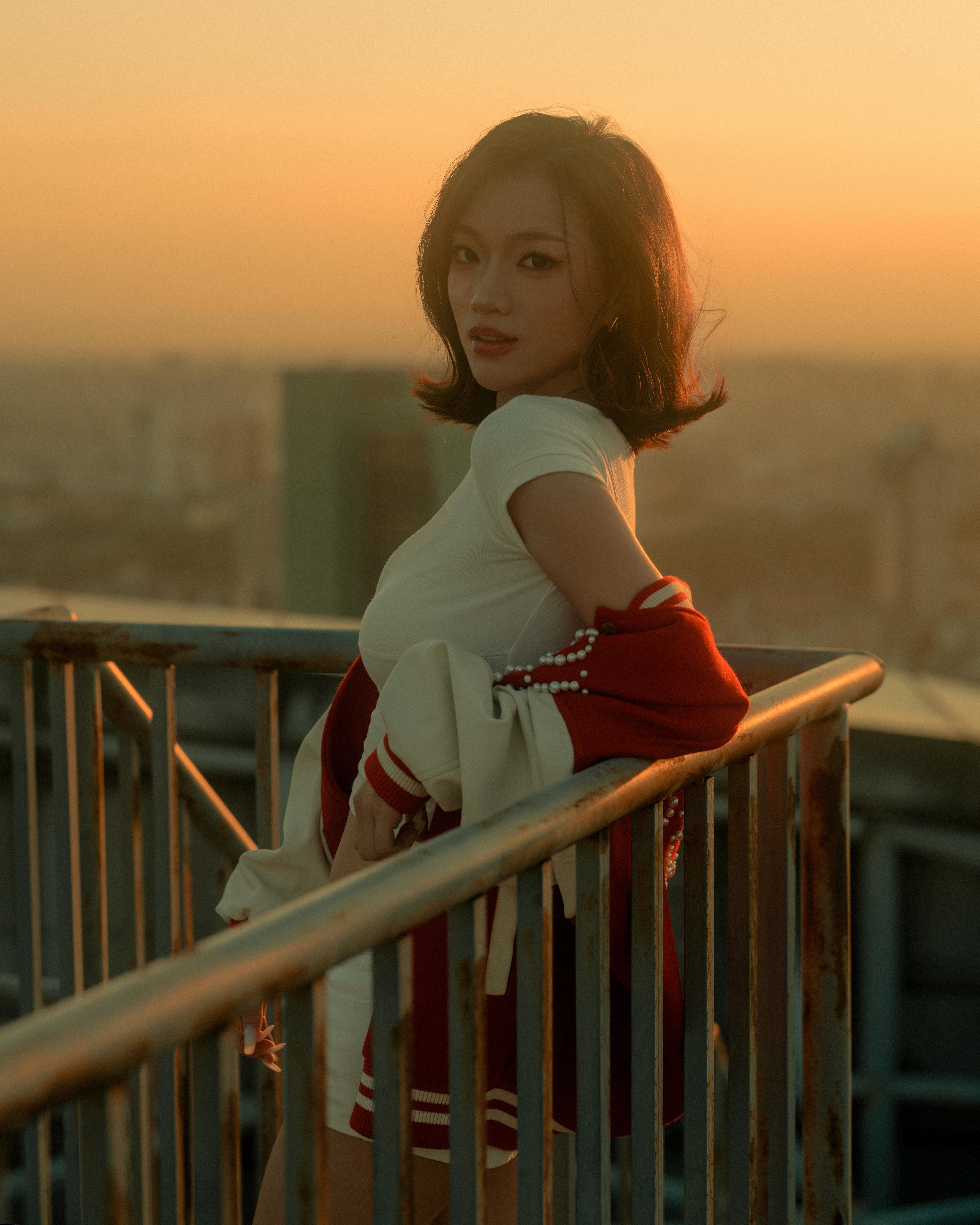 De franc Una dona dreta en una teulada a la posta de sol, amb un paisatge urbà de fons. Foto d'estoc