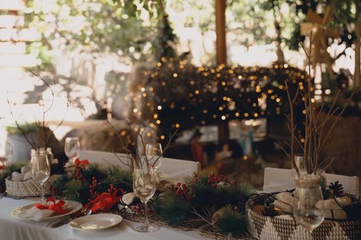 An elegant outdoor table decorated with festive ornaments and warm lights for a holiday celebration.