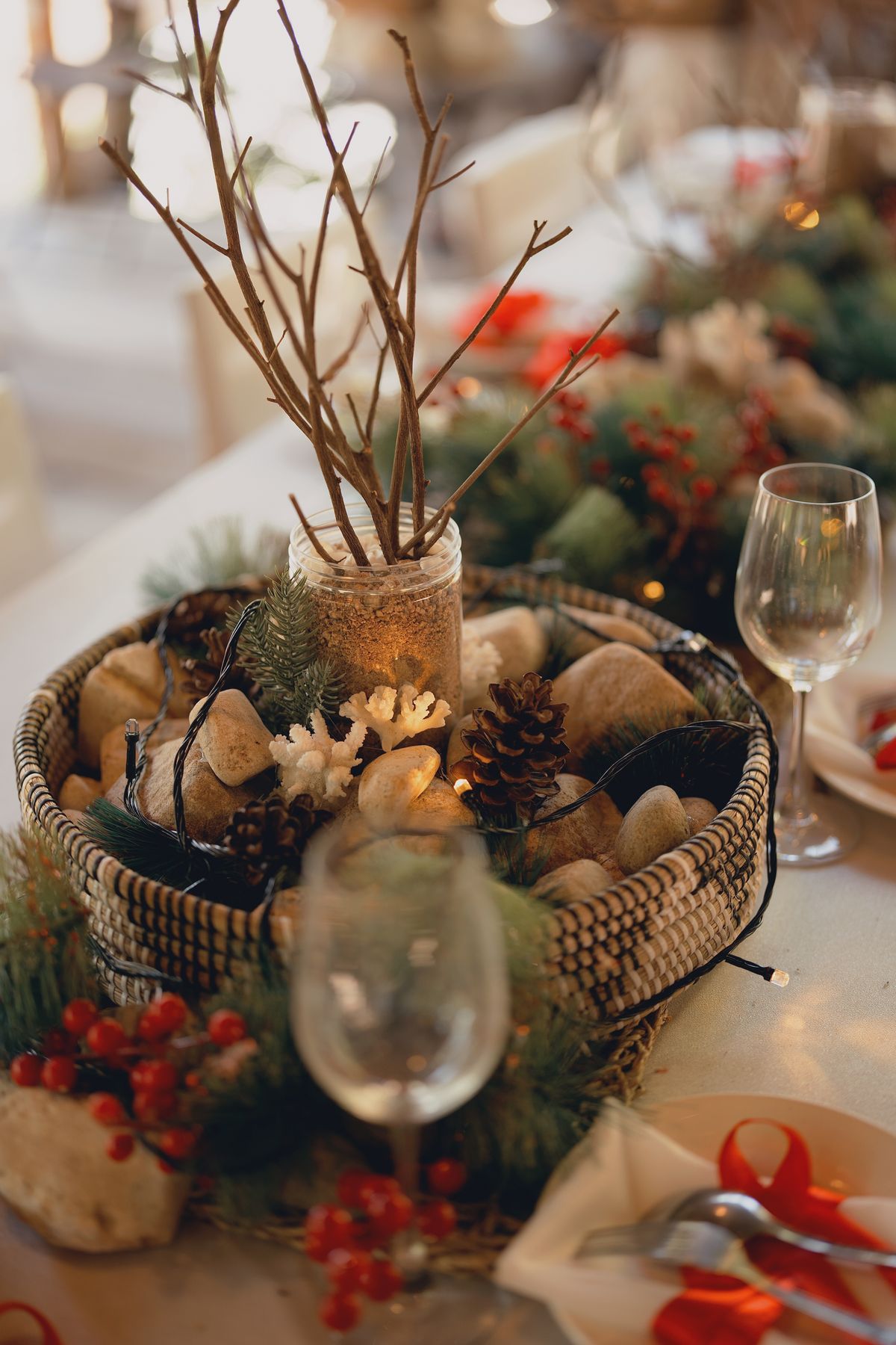Rustic holiday table centerpiece with branches, pinecones, and berries