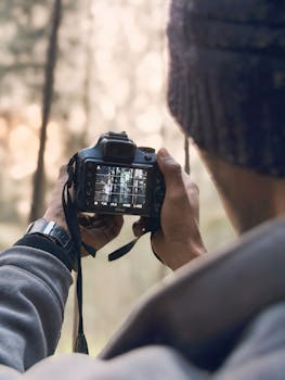 A person photographing nature in the forest with a DSLR camera on a serene day.