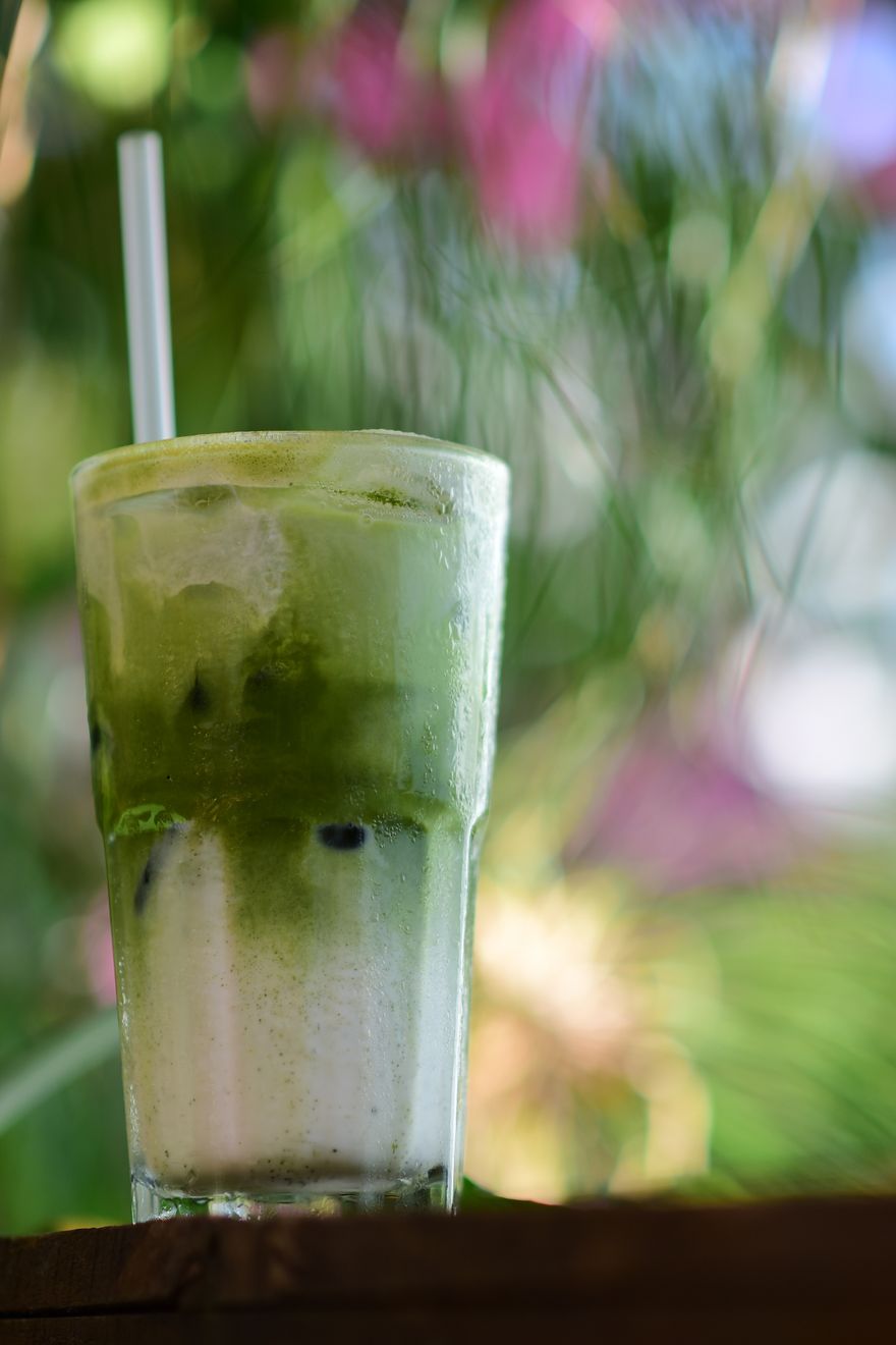 Frothy iced matcha latte in a tall glass in a garden setting, photo by Sóc Năng Động on Pexels