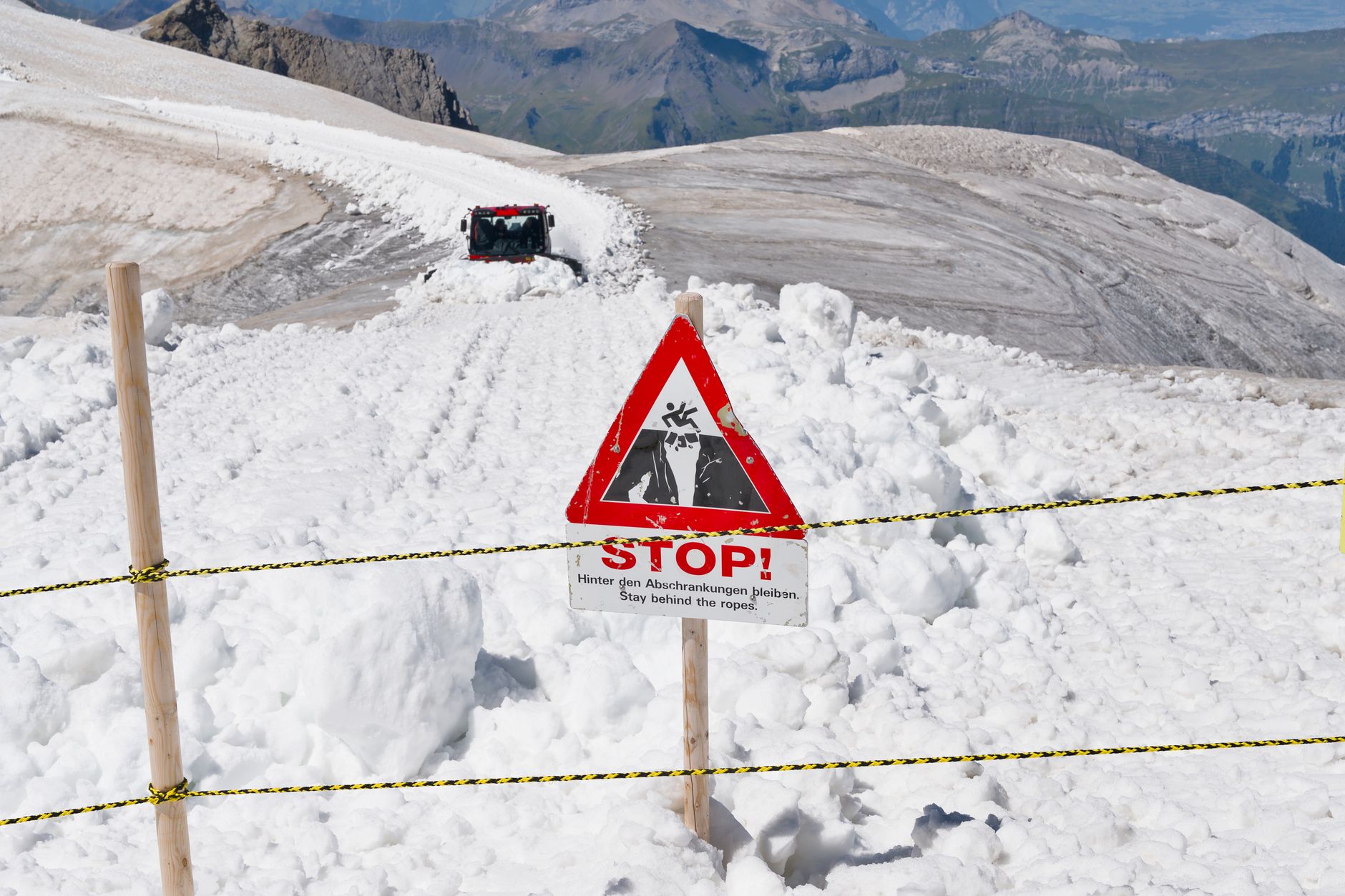 Avalanche warning sign on snowy trail in Swiss Alps with panoramic mountain views.