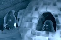 Intricate ice igloo sculpture featuring penguin figurines in an icy environment.
