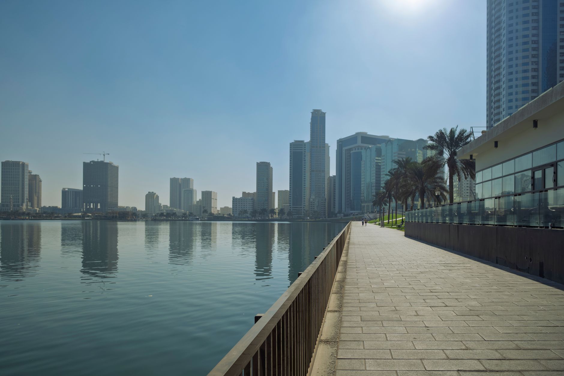 Scenic view of Sharjah's skyline and waterfront promenade, peaceful and serene atmosphere.