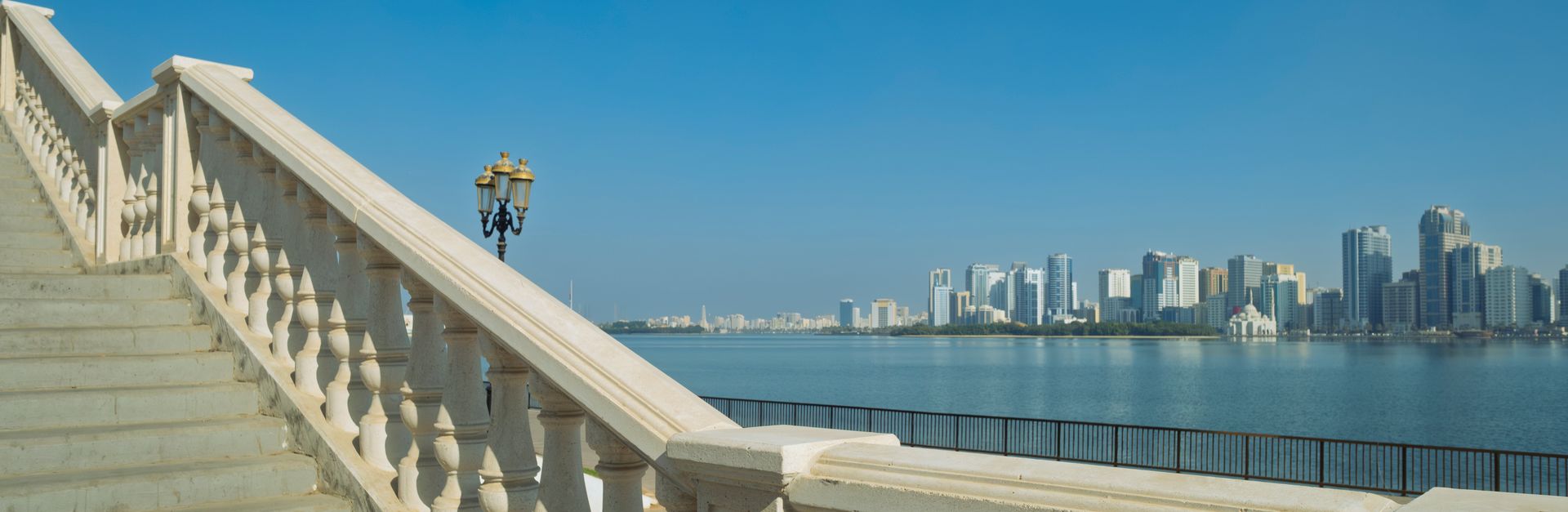 Elegant corniche view in Sharjah with steps leading to waterfront skyline.