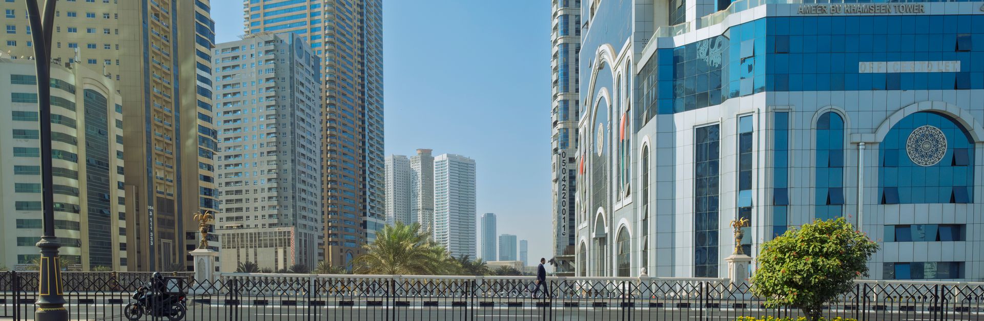 Urban landscape of Sharjah, UAE featuring modern skyscrapers under a clear blue sky.
