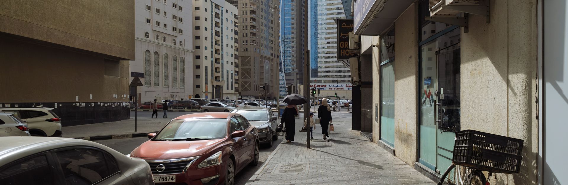 A lively street scene in Sharjah, UAE with bustling pedestrians and cars against a backdrop of skysc