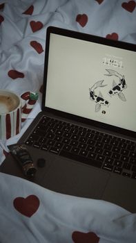 A comfortable setup featuring a laptop and coffee mug on a heart-patterned blanket, ideal for work-from-home inspiration.