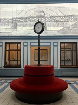 Classic clock with red circular seating, set in a historic Warsaw interior.