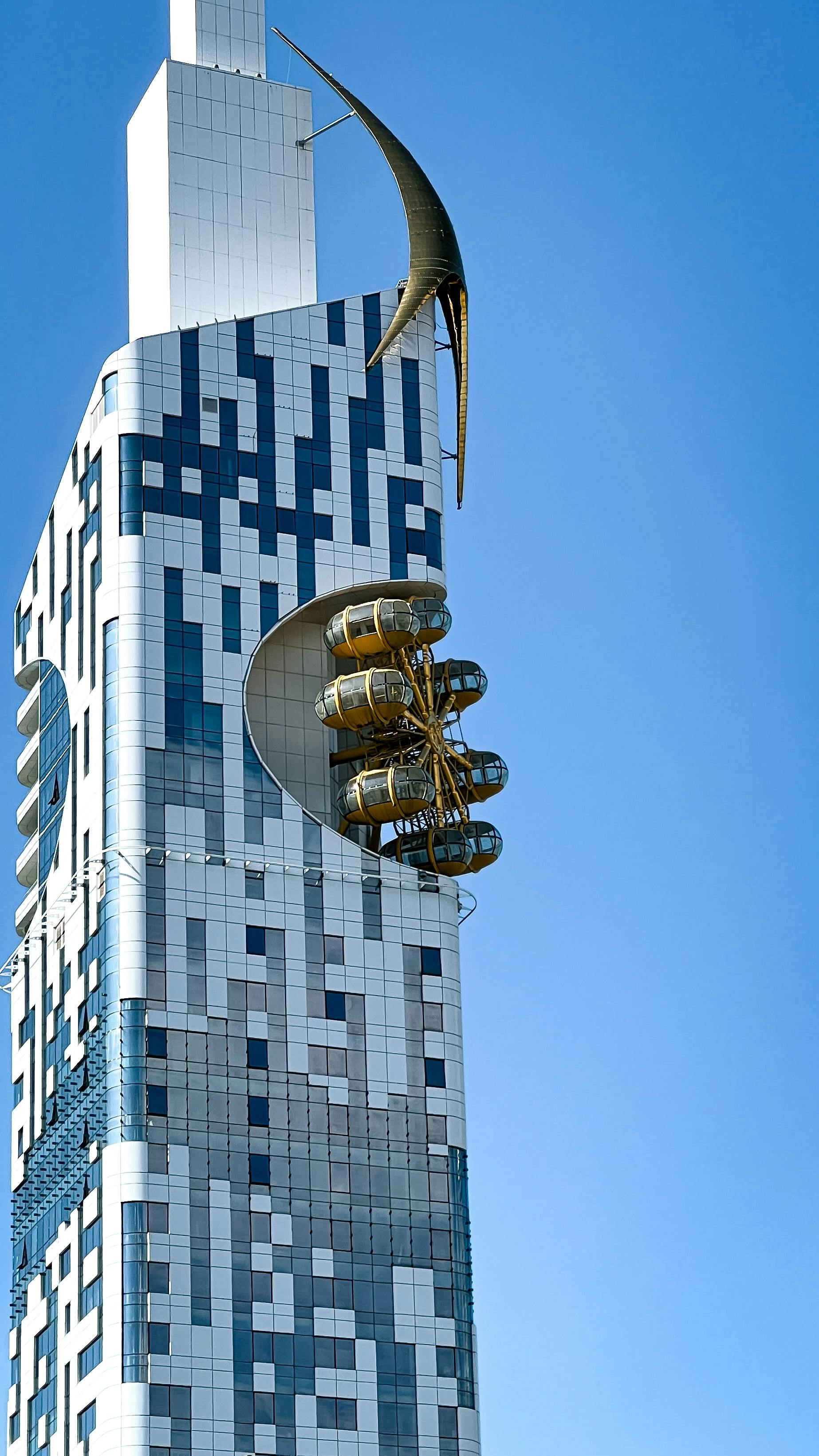 High-tech skyscraper with unique design and sky pods against clear blue sky.