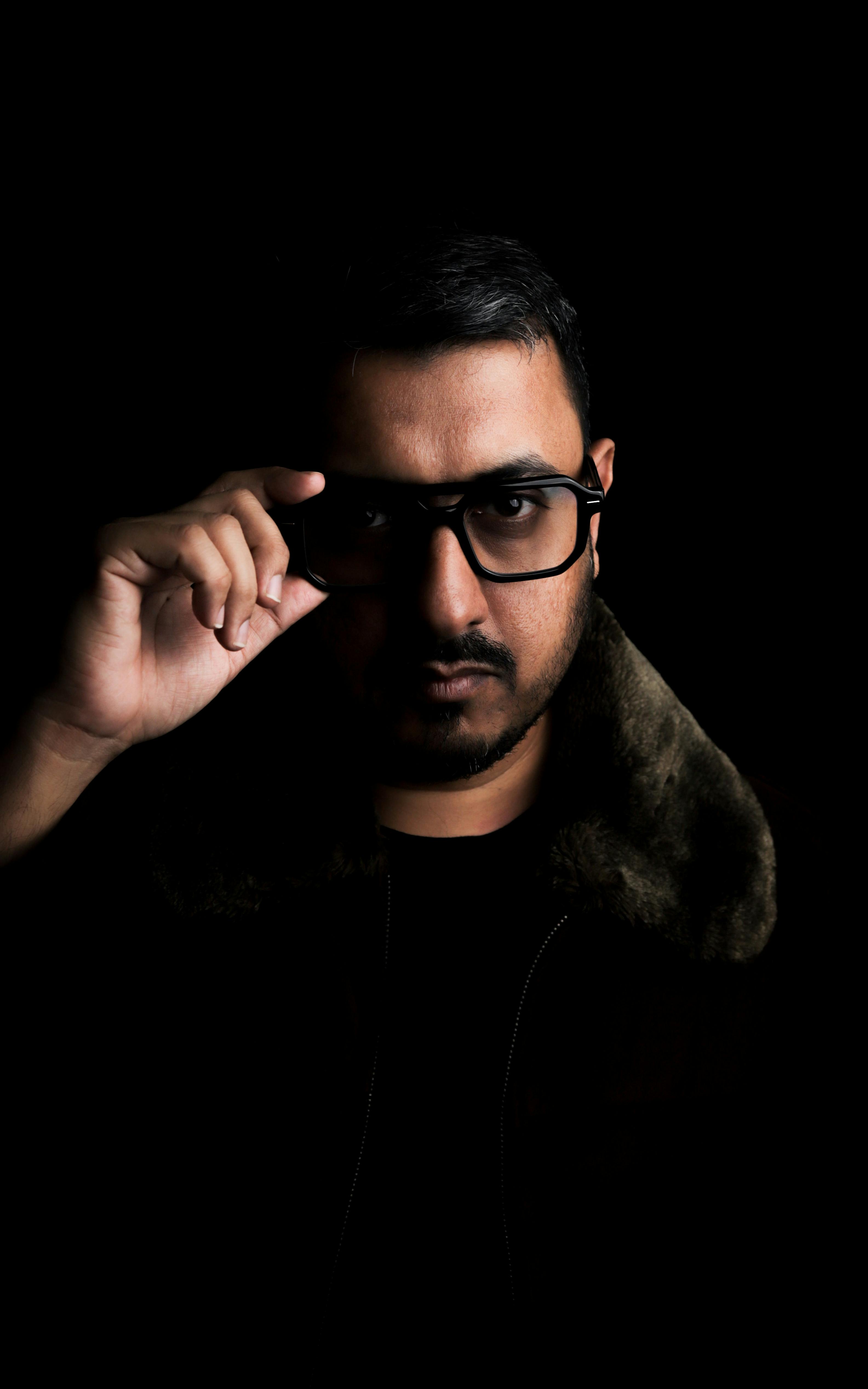 Gratis Slående, lavmælt portrett av en mann som justerer brillene sine i mørkt lys. Arkivbilde