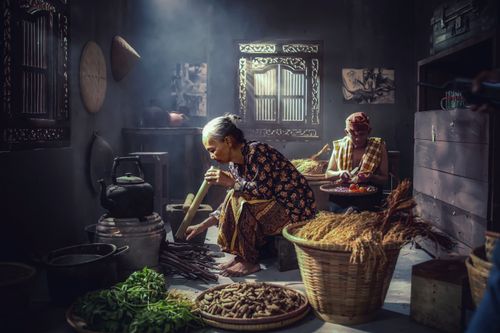 Free Intimate moment in an Indonesian kitchen with two adults preparing food using traditional methods. Stock Photo