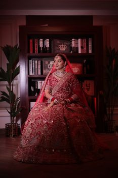 Stunning portrait of a bride in intricate red traditional wedding dress indoors.