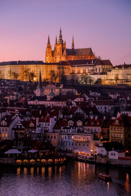 Stunning twilight view of Prague Castle and Vltava River, with illuminated architecture against a vibrant sky.
