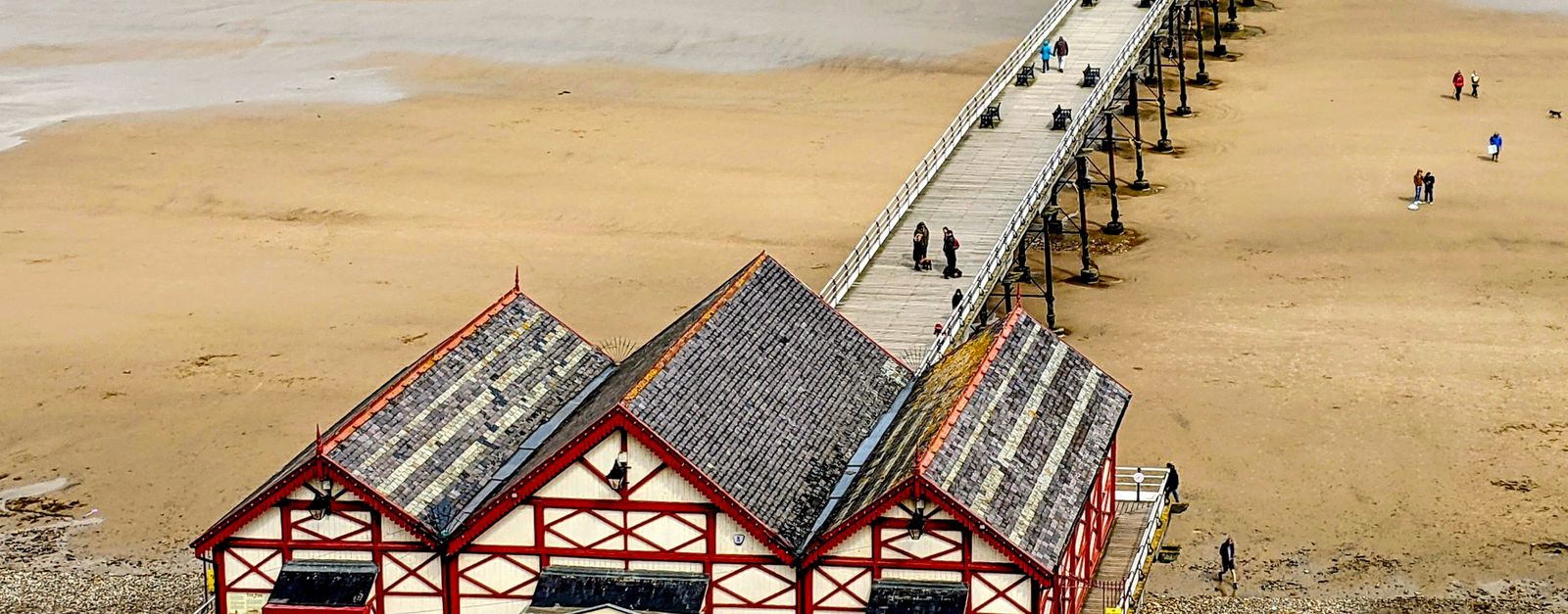 A picturesque aerial view of Saltburn-by-the-Sea's Victorian pier and beach scene in England.