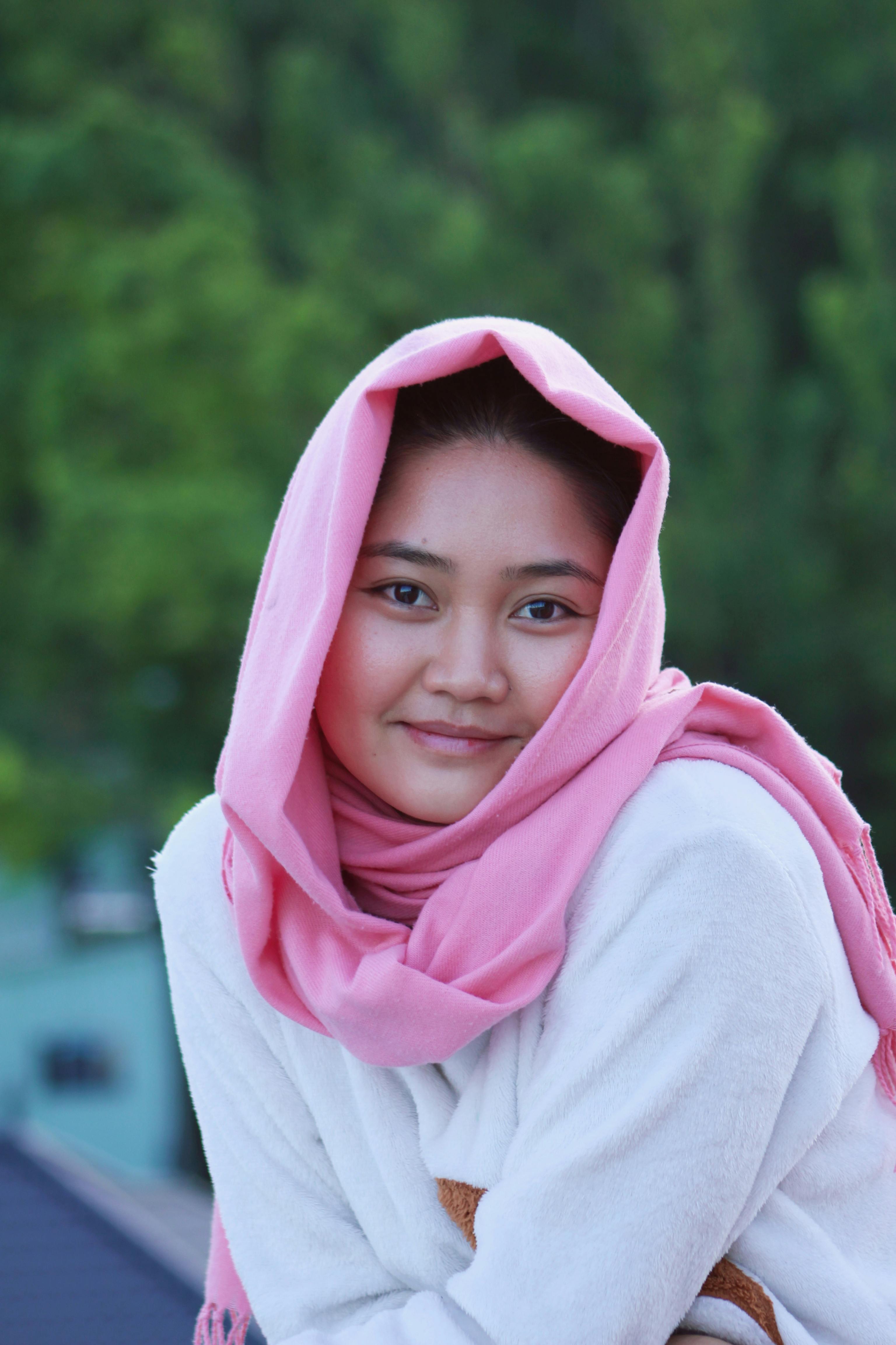 De franc Retrat d'una dona jove amb un hijab rosa, somrient càlidament a l'aire lliure. Foto d'estoc