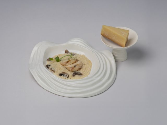 A gourmet risotto with mushrooms and chicken, served with Parmesan cheese.