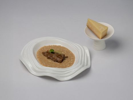 Elegant risotto decorated with herbs, paired with a slice of Parmesan cheese.