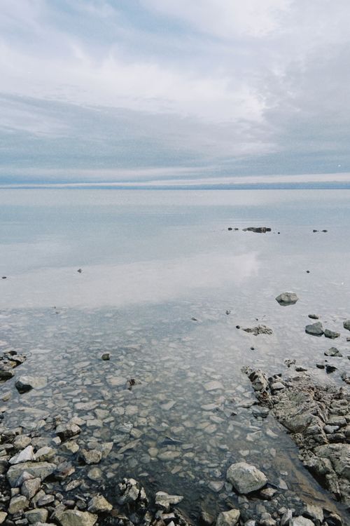 Free Serene view of Lake Balkhash's rocky shoreline in Konaev, Kazakhstan, under cloudy skies. Stock Photo