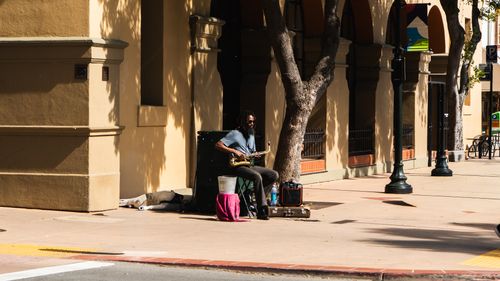 Free A street musician playing saxophone on a sunny day, adding lively tunes to the urban environment. Stock Photo