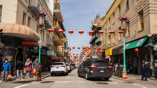 Free Vibrant street view of Chinatown in San Francisco, featuring lanterns, cars, and pedestrians during the day. Stock Photo