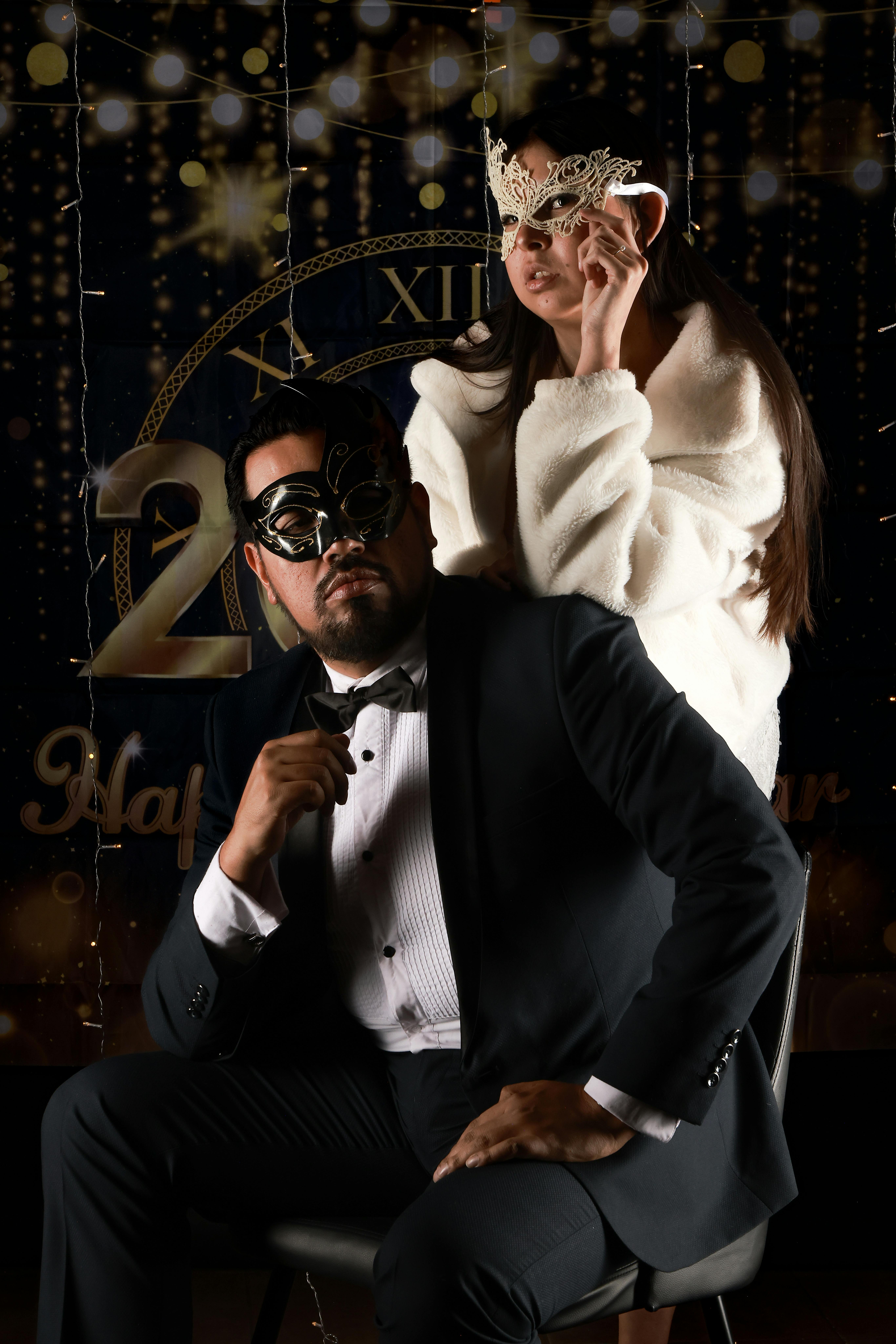 Kostenlos Ein stilvolles Paar mit Masken posiert für ein Neujahrsfoto. Stock-Foto