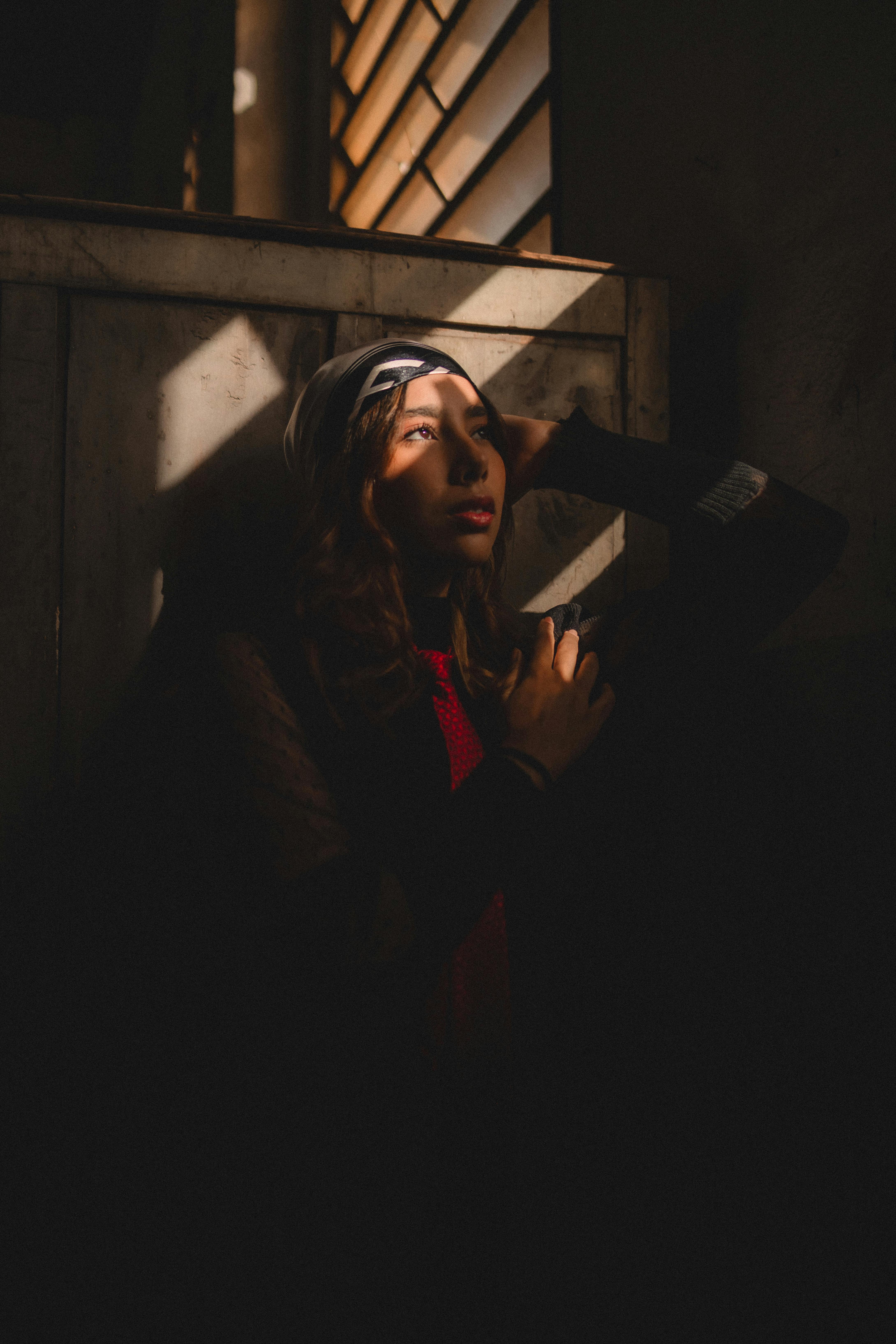 無料 ドラマチックな照明の中で瞑想する女性が神秘的な雰囲気を醸し出しています。 写真素材