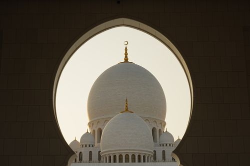Free Capture of Sheikh Zayed Grand Mosque domes framed by an arch, highlighting Islamic architecture. Stock Photo