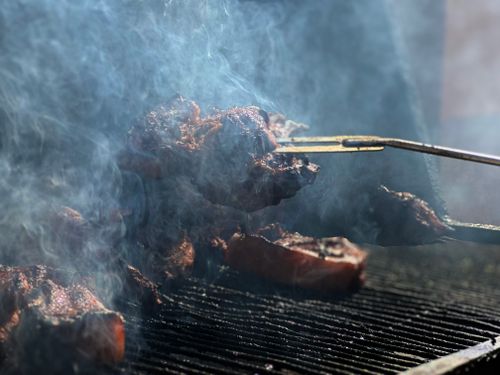 Free Close-up of meat sizzling on a smoky barbecue grill outdoors. Stock Photo