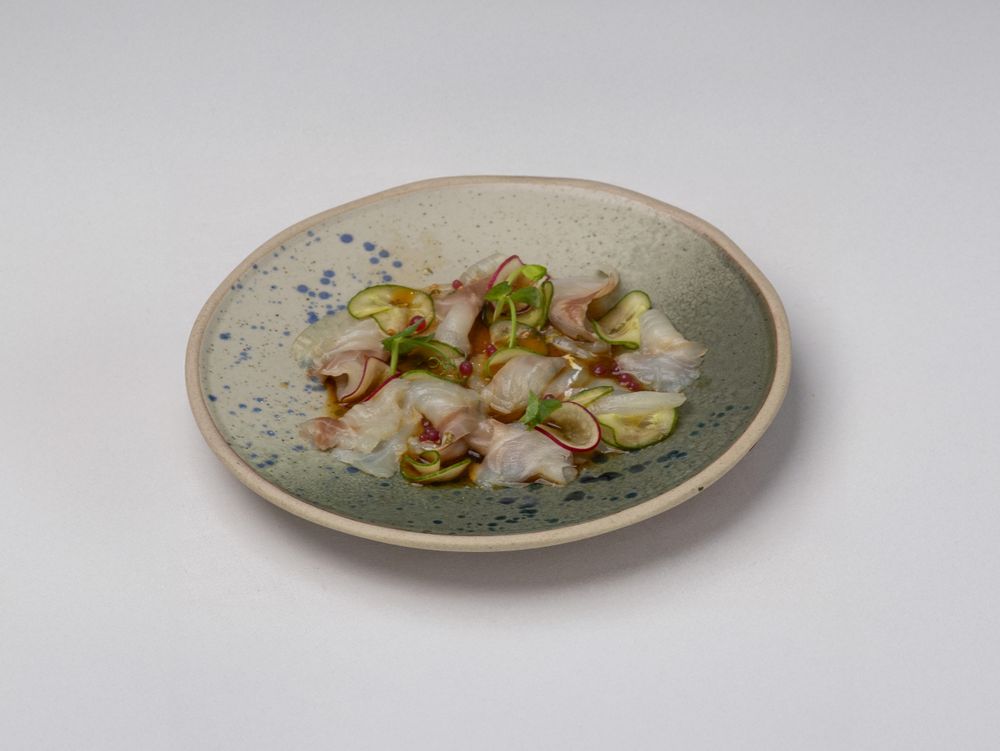 Crudo di mare servito su piatto in ceramica screziata di blu