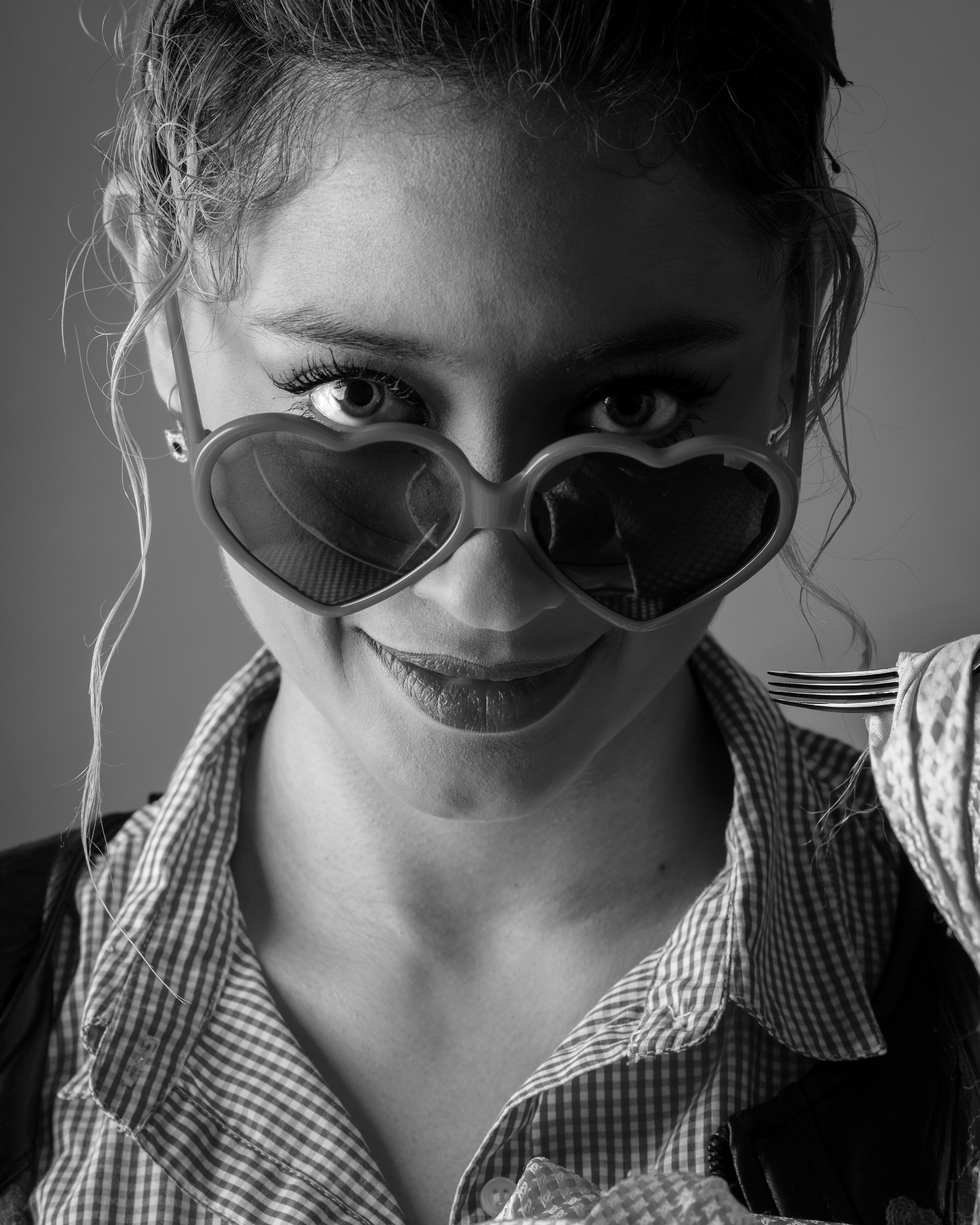 De franc Dona elegant amb ulleres de sol en forma de cor, capturada en un retrat modern en blanc i negre. Foto d'estoc