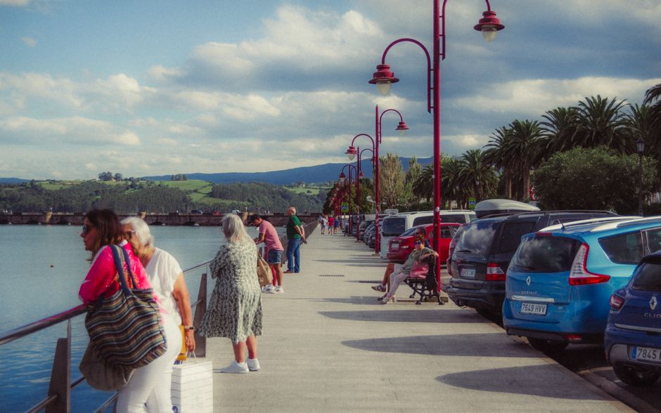 La gente pasea por un pintoresco paseo marítimo en Asturias, España, con impresionantes vistas de la costa y la montaña.