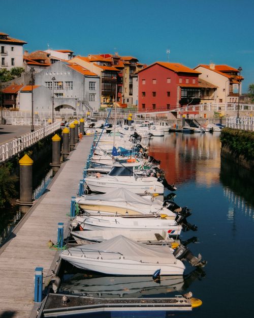 Free Sunny day at the vibrant marina in Asturias, Spain with boats and colorful buildings. Stock Photo