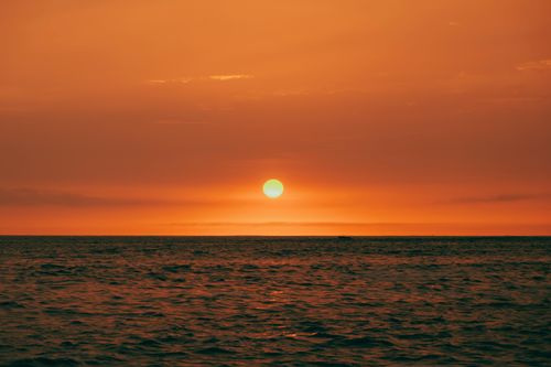 Free A breathtaking ocean sunset with vibrant orange sky, perfect for tranquil and scenic backgrounds. Stock Photo